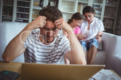 Worried man sitting at table with bills and laptop