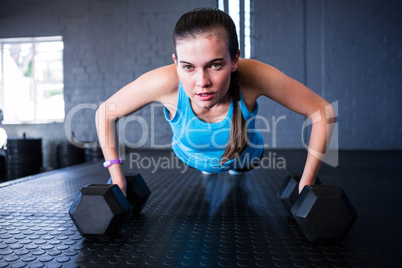 Sporty woman doing push-ups with dumbbells