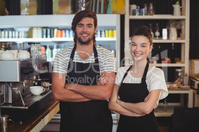 Waiter and waitress standing with arms crossed in cafe