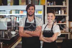 Waiter and waitress standing with arms crossed in cafe