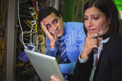 Bored technician looking at colleague while analyzing server