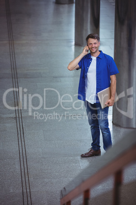 Handsome man holding laptop and talking on mobile phone