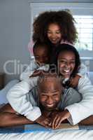 Happy family lying on top of each other on bed