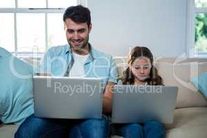 Father and daughter using laptop in the living room