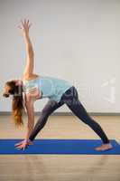 Woman performing triangle pose on exercise mat