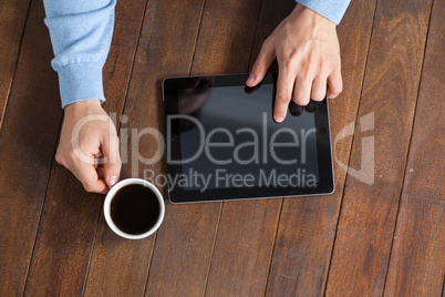 Man using digital tablet while having cup of coffee