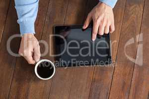 Man using digital tablet while having cup of coffee