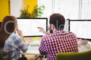 Businessman showing something to female coworker on computer