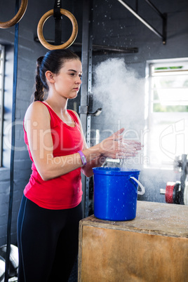 Female athlete rubbing sports chalk on hands in gym