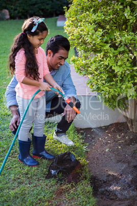 Father and daughter spraying water to plant