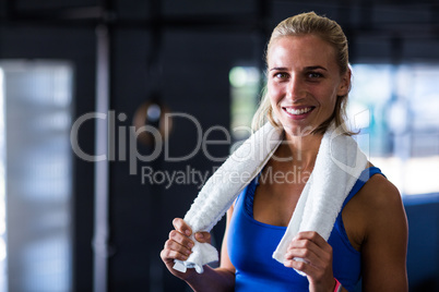 Portrait of happy fit woman with towel in gym