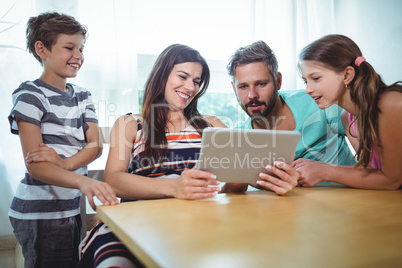 Family using digital tablet while sitting at table