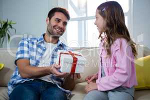 Father giving gift to daughter in the living room