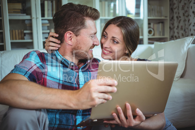 Happy couple using laptop in living room