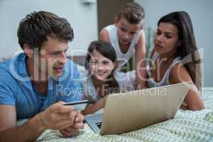 Family doing online shopping on laptop in bedroom