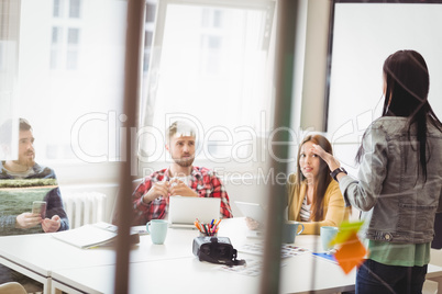 Coworkers looking at businesswoman giving presentation