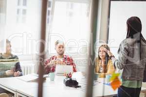 Coworkers looking at businesswoman giving presentation