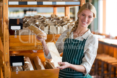 Female staff packing a bread in paper bag