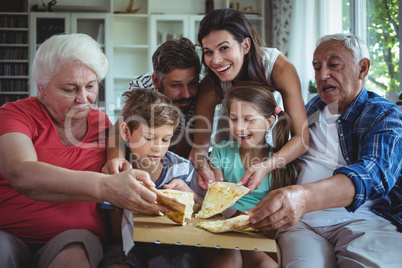 Multi-generation family having pizza in living room