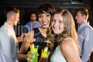 Female friends holding glasses of cocktail in bar
