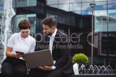 Businesspeople discussing on digital tablet and laptop