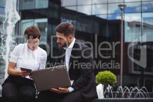 Businesspeople discussing on digital tablet and laptop