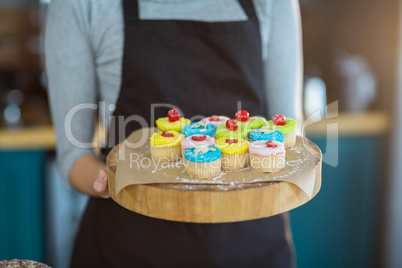 Waitress holding cup cake on tray in cafÃ?Â©