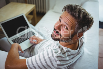 Smiling man using his laptop in living room