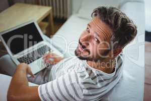 Smiling man using his laptop in living room
