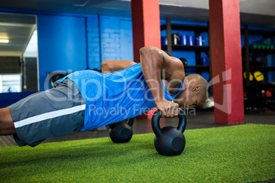 Male athlete doing push-ups with kettlebells