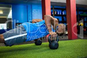 Male athlete doing push-ups with kettlebells
