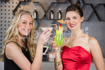 Female friends holding glass of cocktail in bar