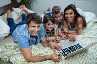 Family doing online shopping on laptop in bedroom at home