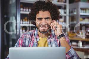 Man using laptop while talking on mobile phone