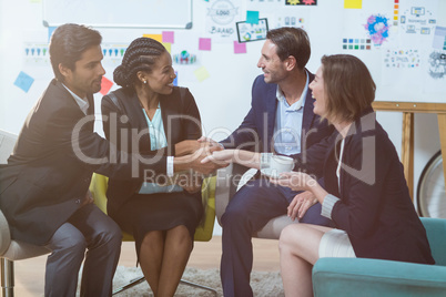 Group of businesspeople shaking hands with each other in front of whiteboard