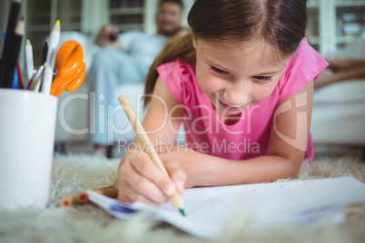 Smiling girl lying on the floor and drawing