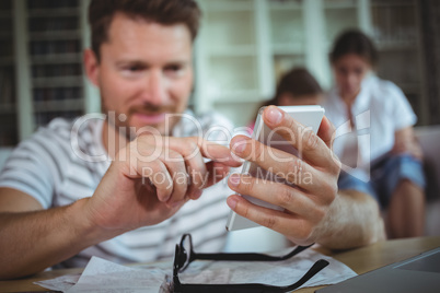 Happy man sitting at table and using his mobile phone