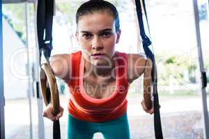 Portrait of confident athlete holding gymnastic rings