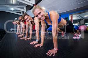 Portrait of happy people doing push-ups in gym
