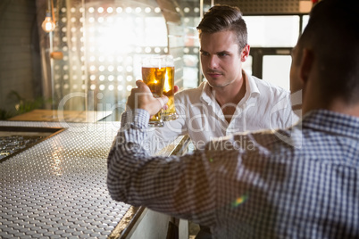 Two men toasting a glass of beer