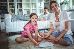 Mother and daughter sitting on the floor and drawing