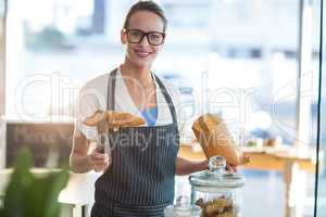 Smiling waitress packing croissants in paper bag at cafÃ?Â©