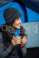 Smiling hiker having a cup of coffee in tent