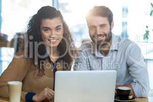 Smiling couple using laptop in cafÃ?Â©