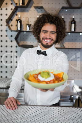 Waiter serving bowl of snack in bar counter
