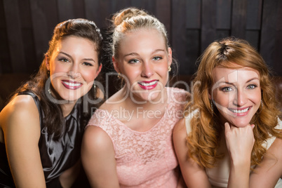 Smiling female friends sitting together in sofa at bar