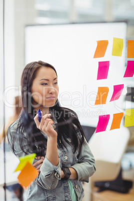 Creative businesswoman looking at multi colored sticky notes