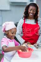 Girl preparing cake with mother