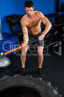Shirtless man exercising with sledgehammer