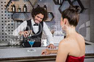 Waiter pouring cocktail in womans glass at bar counter